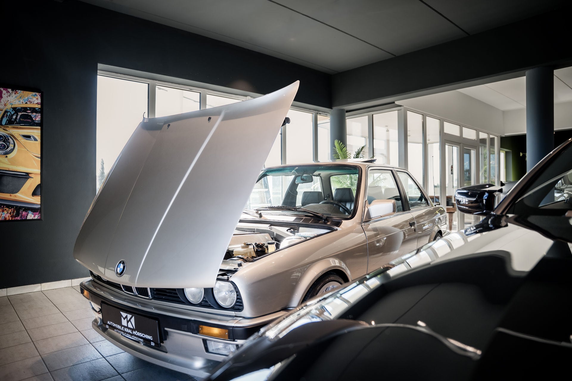 BMW 3er E30 mit geöffneter Motorhaube im Showroom von M.K. Automobile