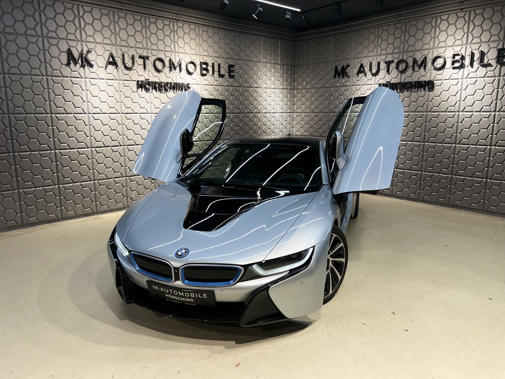 BMW i8 mit geöffneten Flügeltüren im Showroom